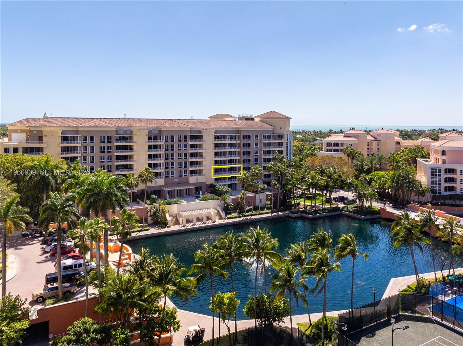 An exterior view of a multi-story residential building overlooking a lake and palm trees — 765 Crandon Blvd # 306, Key Biscayne FL 33149, KEY BISCAYNE, FL