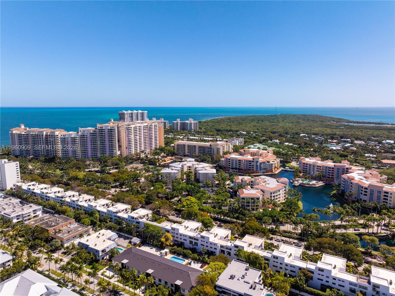 An aerial view shows a coastal residential complex with multiple buildings, pools, and lush landscaping — 765 Crandon Blvd # 306, Key Biscayne FL 33149, KEY BISCAYNE, FL