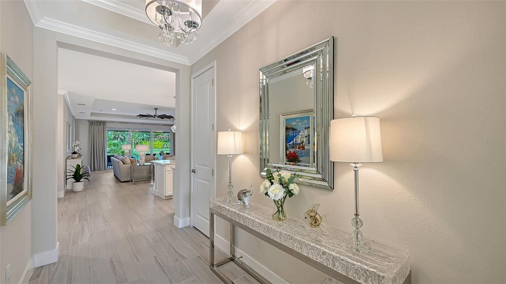 A bright foyer features a console table with lamps, a mirror, and a view into the living area — 5521 BLUE WATER BOULEVARD, SARASOTA, FL