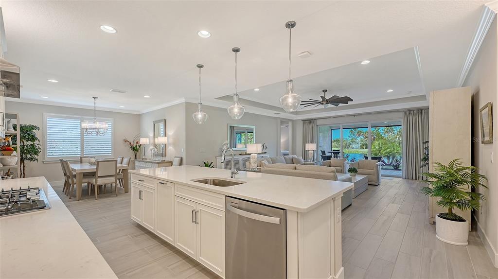 A modern open-concept kitchen and living area with white cabinetry, quartz countertops, and tile flooring — 5521 BLUE WATER BOULEVARD, SARASOTA, FL
