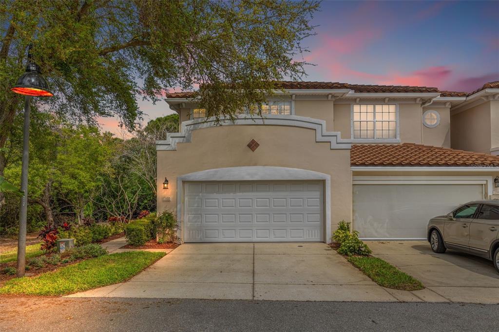A two-story stucco townhouse with a two-car garage and a tile roof at dusk — 252 VALENCIA CIRCLE, ST PETERSBURG, FL