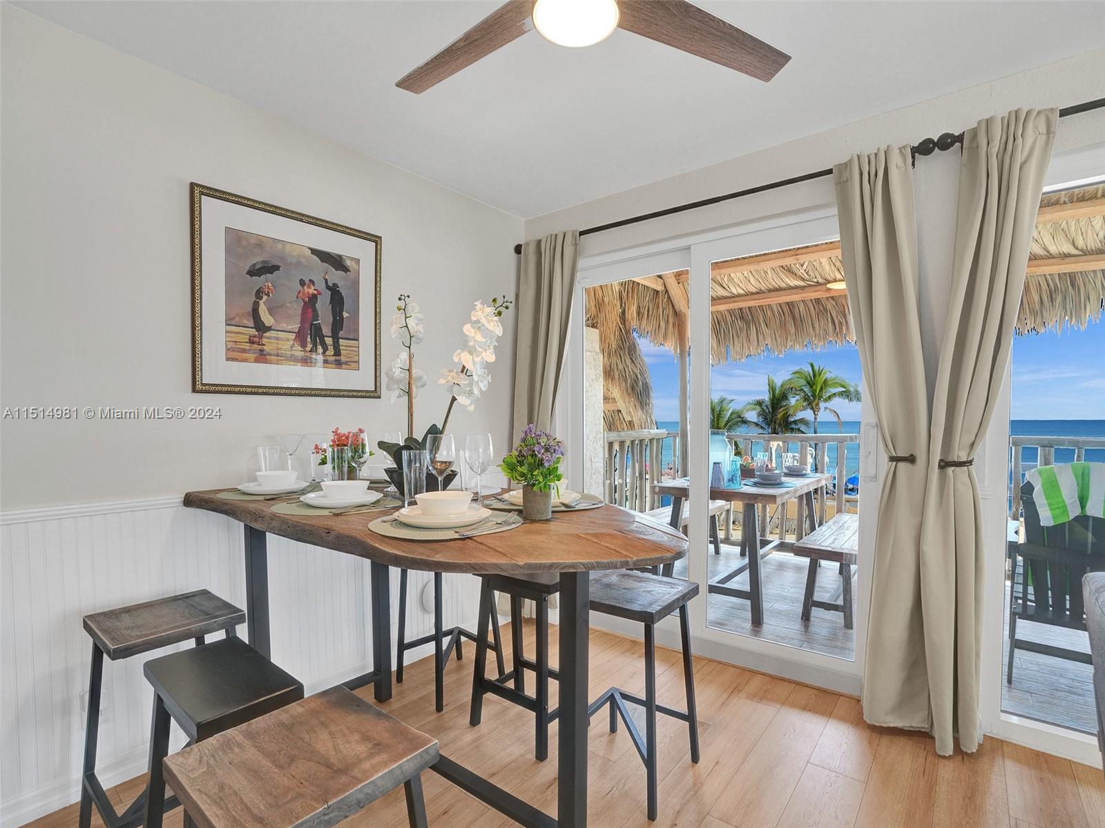 A dining area features a wooden table, stools, and a sliding door leading to a balcony — 900 N Surf Rd # 2, Hollywood FL 33019, HOLLYWOOD, FL