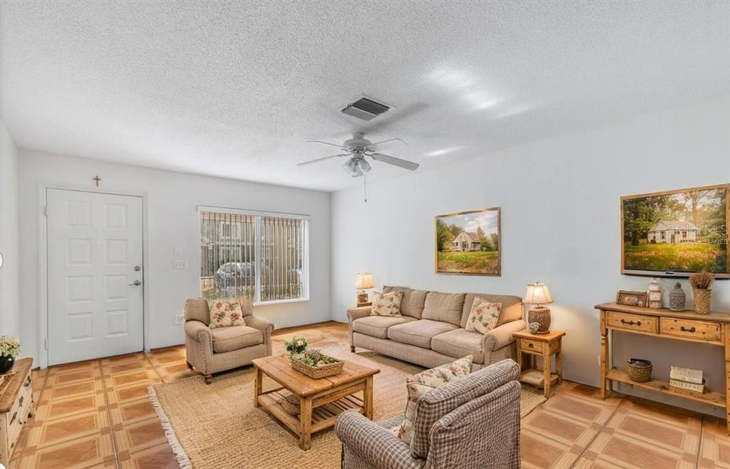 A living room features a beige sofa, two armchairs, a wooden coffee table, and tiled floors — 1907 FLUORSHIRE DRIVE, BRANDON, FL
