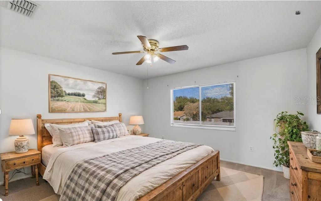 A bedroom features a wooden bed frame, a ceiling fan, and a window with blinds — 1907 FLUORSHIRE DRIVE, BRANDON, FL