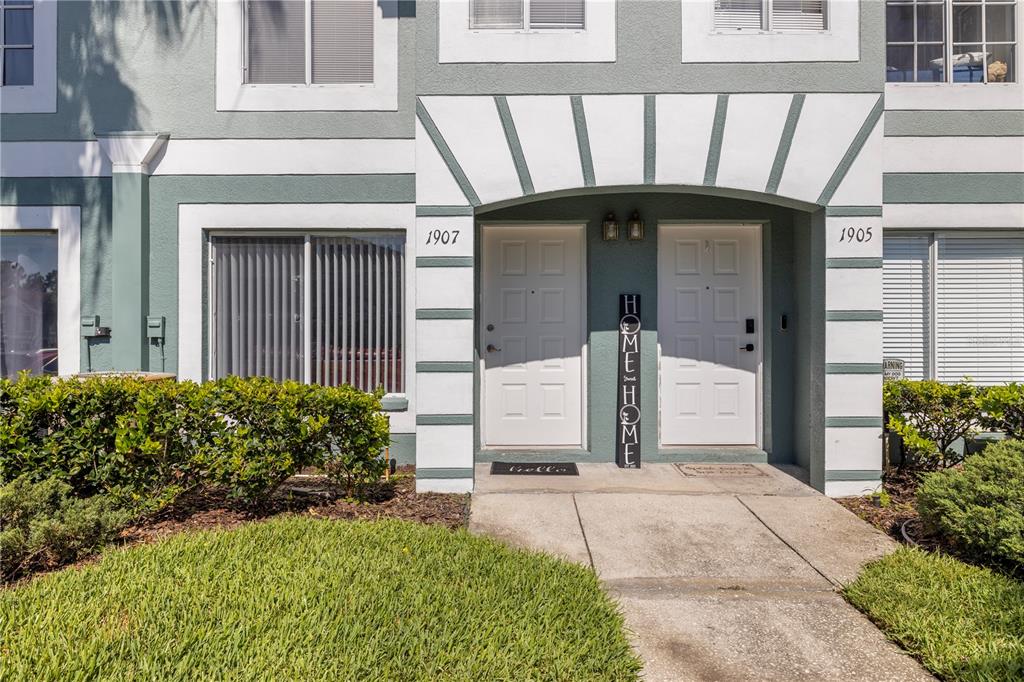 The exterior of a two-story building features two white front doors with address numbers — 1907 FLUORSHIRE DRIVE, BRANDON, FL