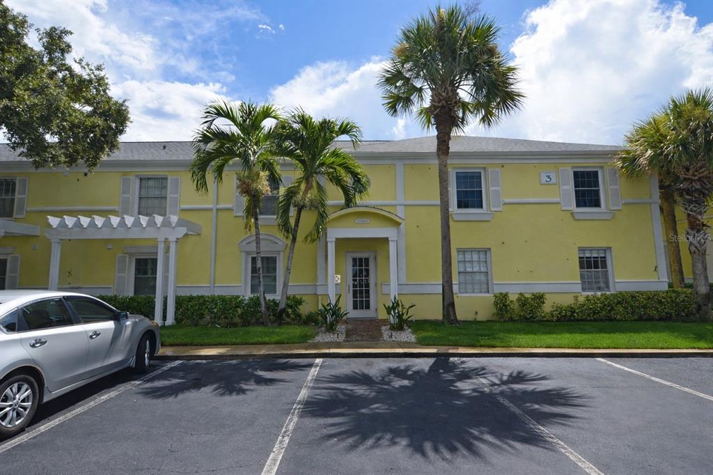 A two-story yellow apartment building with a parking lot in the foreground — 5048 BEACH DRIVE SE UNIT F, ST PETERSBURG, FL