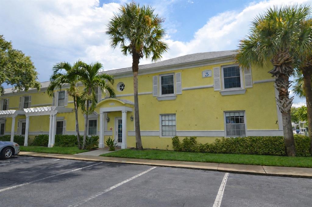 A two-story yellow apartment building with palm trees and a parking lot in front — 5048 BEACH DRIVE SE UNIT F, ST PETERSBURG, FL