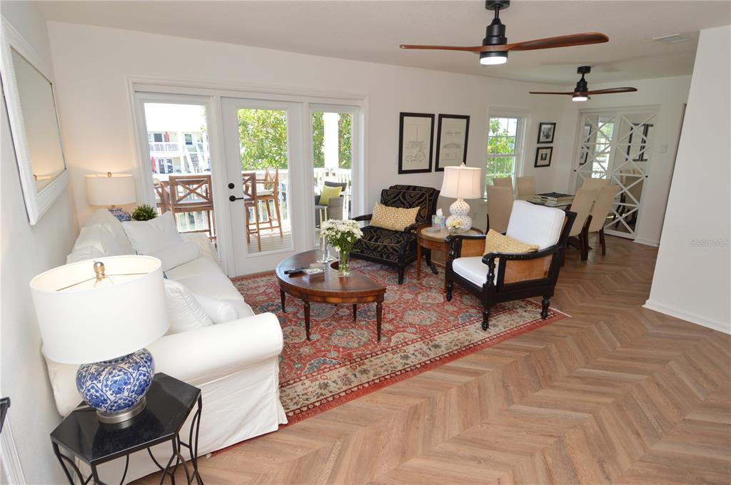 A living room features herringbone wood floors, a patterned area rug, and glass patio doors — 5048 BEACH DRIVE SE UNIT F, ST PETERSBURG, FL