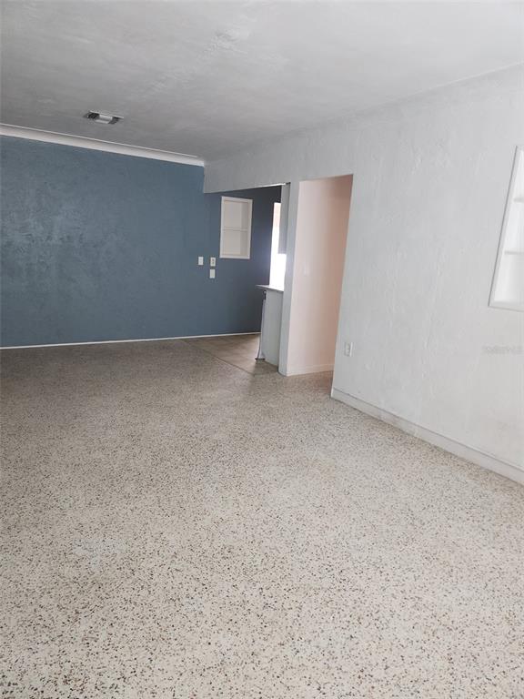 An interior view of a room with terrazzo flooring, white walls, and a blue accent wall — 13406 BOCA CIEGA AVENUE UNIT 4, MADEIRA BEACH, FL