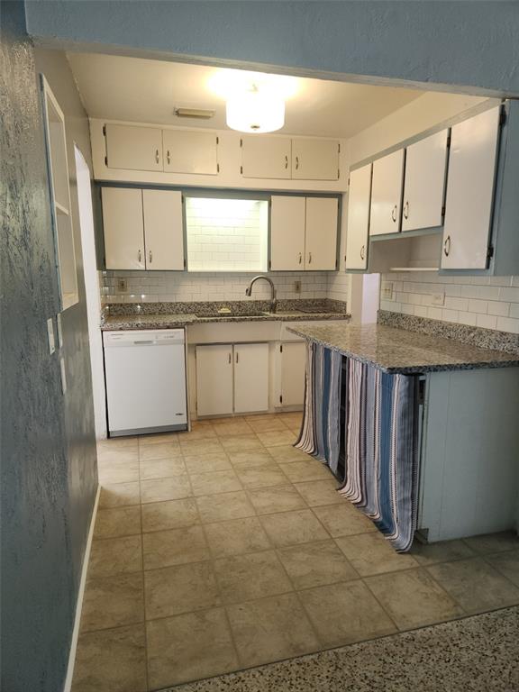 A kitchen features white cabinets, granite countertops, a dishwasher, and a blue-striped curtained island — 13406 BOCA CIEGA AVENUE UNIT 4, MADEIRA BEACH, FL