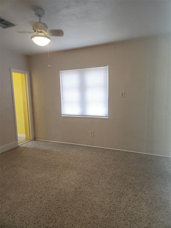 A bedroom with beige walls, a ceiling fan, a window with blinds, and carpeted flooring — 13406 BOCA CIEGA AVENUE UNIT 4, MADEIRA BEACH, FL