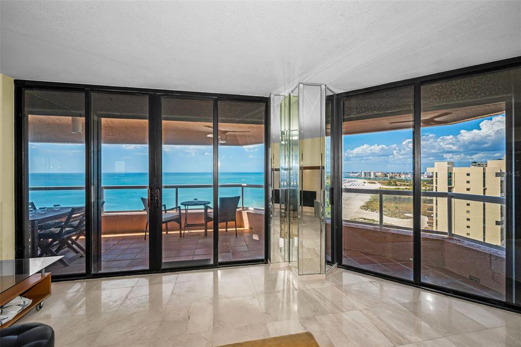 A living room with marble floors features floor-to-ceiling windows overlooking a balcony and the ocean — 1310 GULF BOULEVARD UNIT Penthouse A, CLEARWATER BEACH, FL