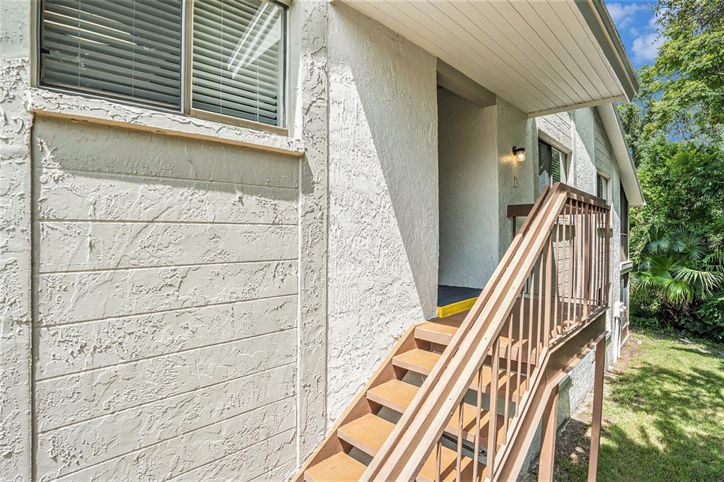 An exterior view of a building with a wooden staircase leading to a second-floor entrance — 12308 EAGLESWOOD DRIVE UNIT D, HUDSON, FL