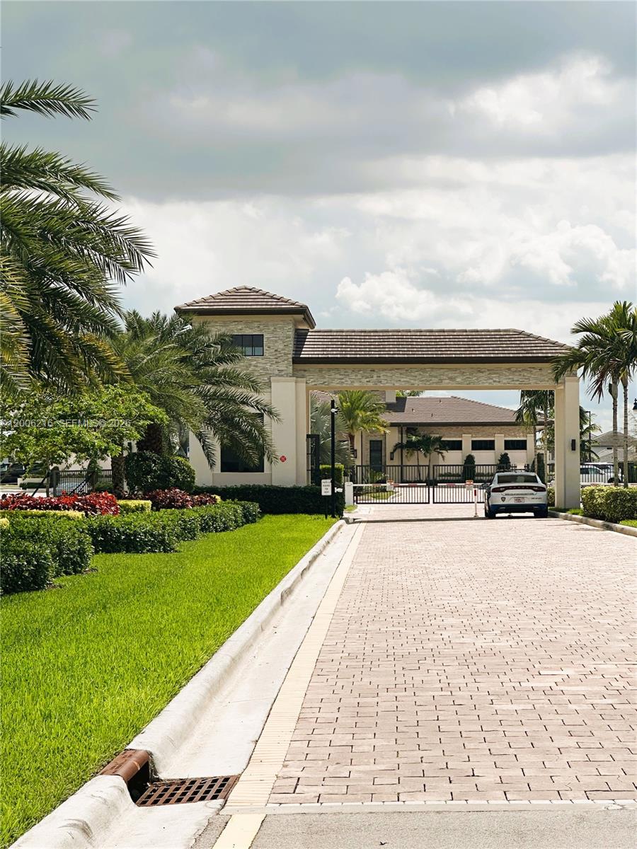A paved driveway leads to a gated entrance with a stone-accented guardhouse and palm trees — 4363 SW 173rd Ave, Miramar FL 33029, MIRAMAR, FL