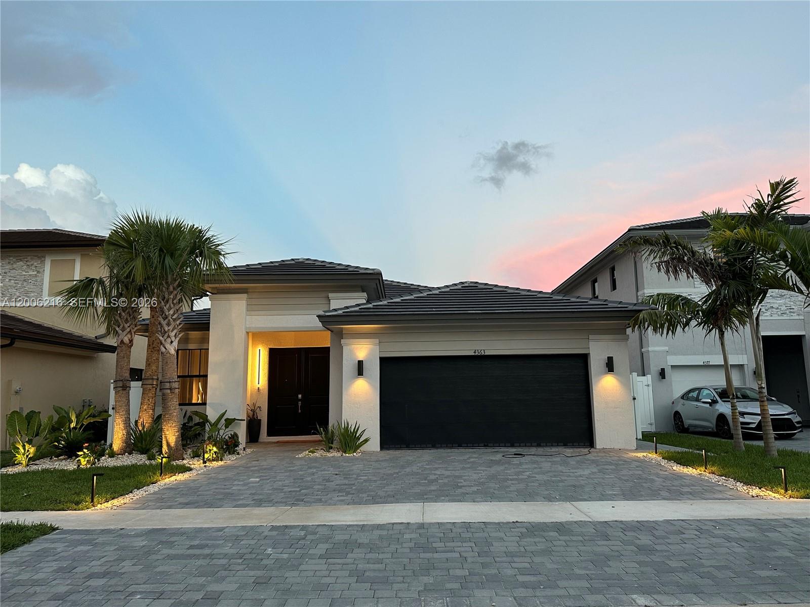 A modern single-story house with a dark garage door, paved driveway, and palm trees — 4363 SW 173rd Ave, Miramar FL 33029, MIRAMAR, FL