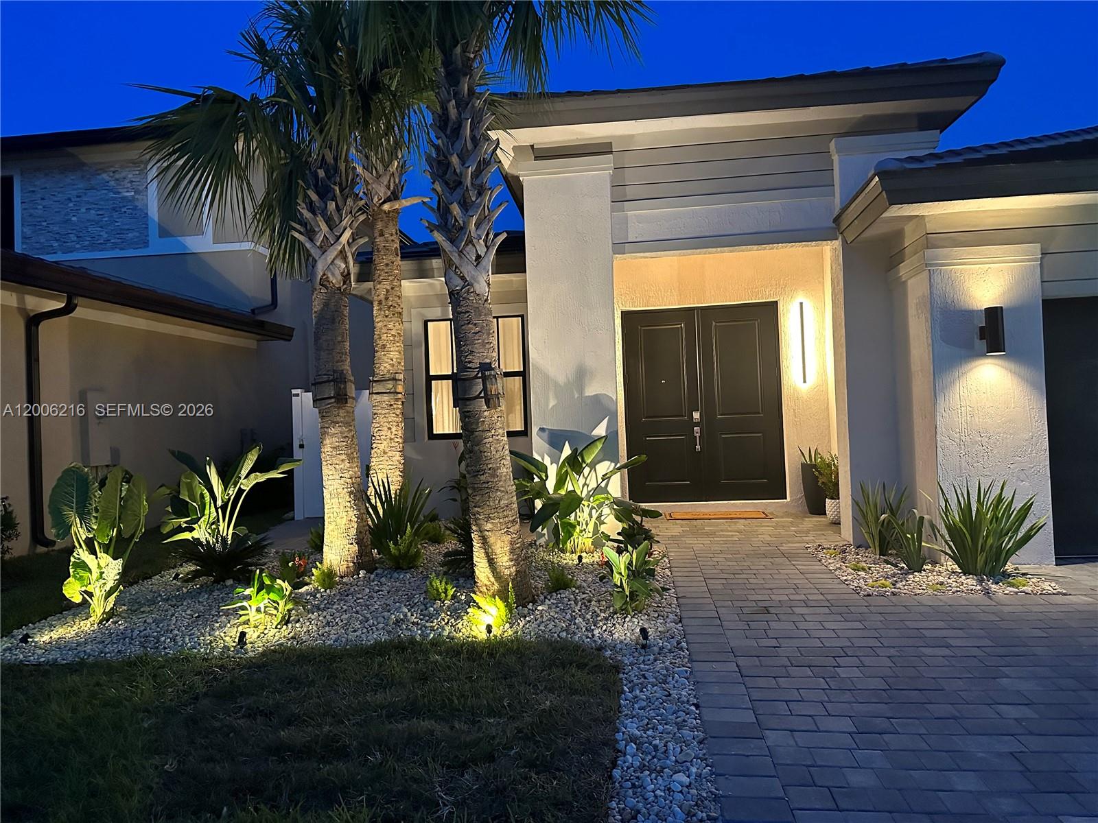 The exterior of a modern house features a paved walkway, palm trees, and landscape lighting — 4363 SW 173rd Ave, Miramar FL 33029, MIRAMAR, FL