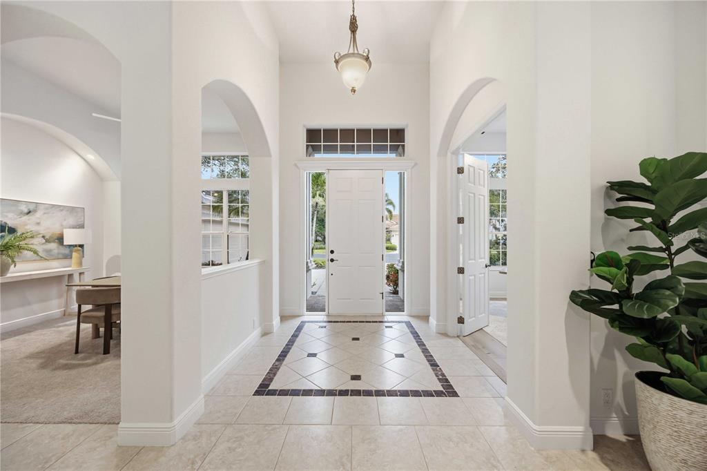 A bright foyer features arched doorways, a tiled floor with a decorative border, and a chandelier — 903 TRANQUILITY CIRCLE, OSPREY, FL