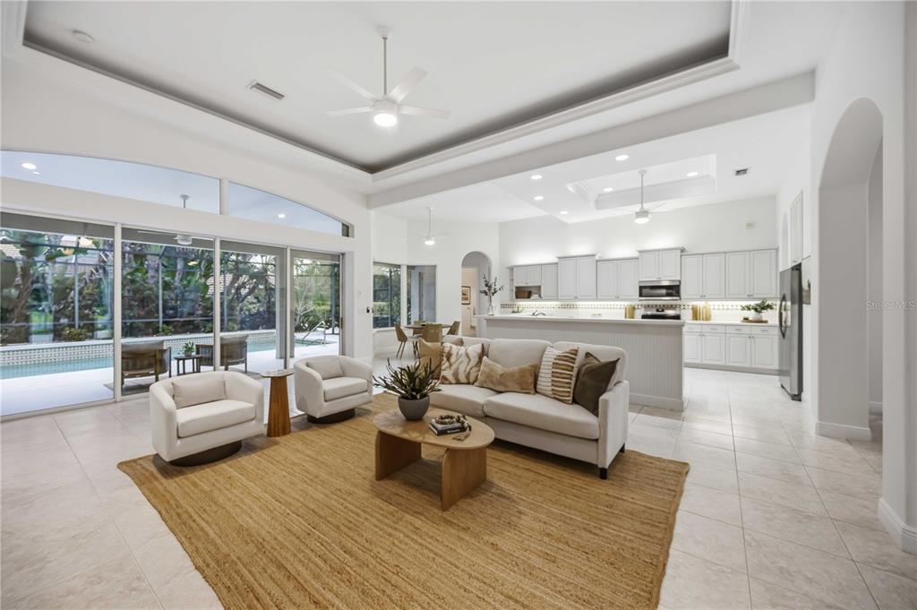 An open-concept living room and kitchen featuring white cabinetry, tile floors, and a pool view — 903 TRANQUILITY CIRCLE, OSPREY, FL