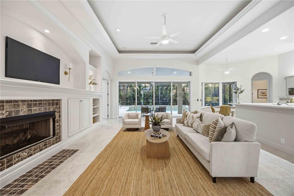 A living room features a fireplace, a large sofa, and sliding glass doors to a pool — 903 TRANQUILITY CIRCLE, OSPREY, FL