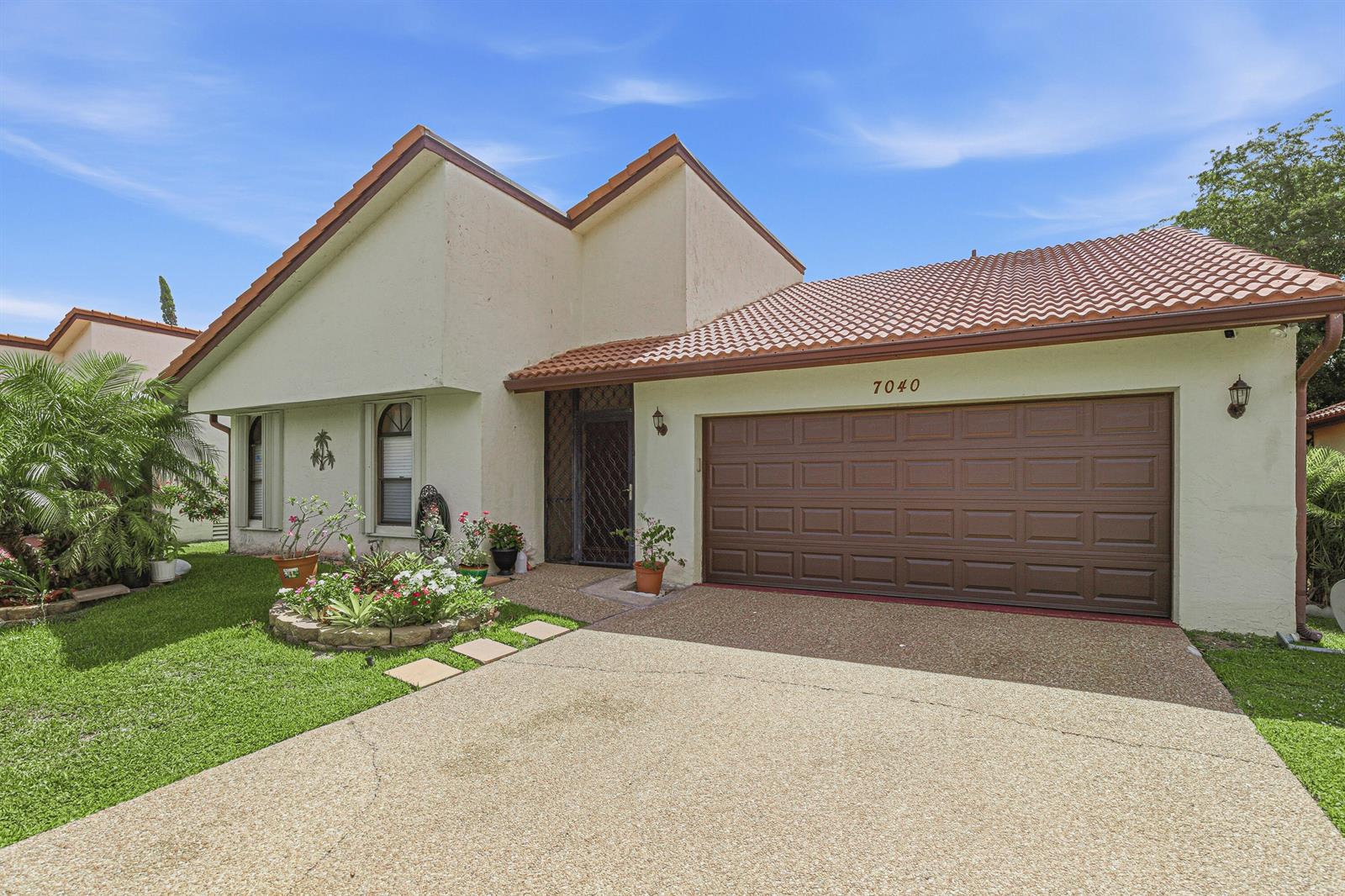A single-story house with a brown tile roof, beige stucco walls, and a two-car garage — 7040 Golf Pointe Circle, Tamarac FL 33321, TAMARAC, FL