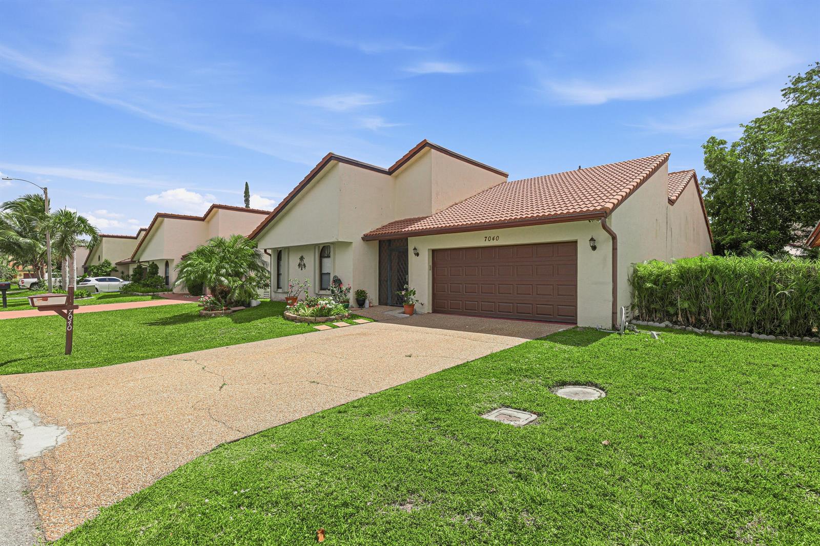 A single-story house with a brown garage door, tiled roof, and a green lawn — 7040 Golf Pointe Circle, Tamarac FL 33321, TAMARAC, FL