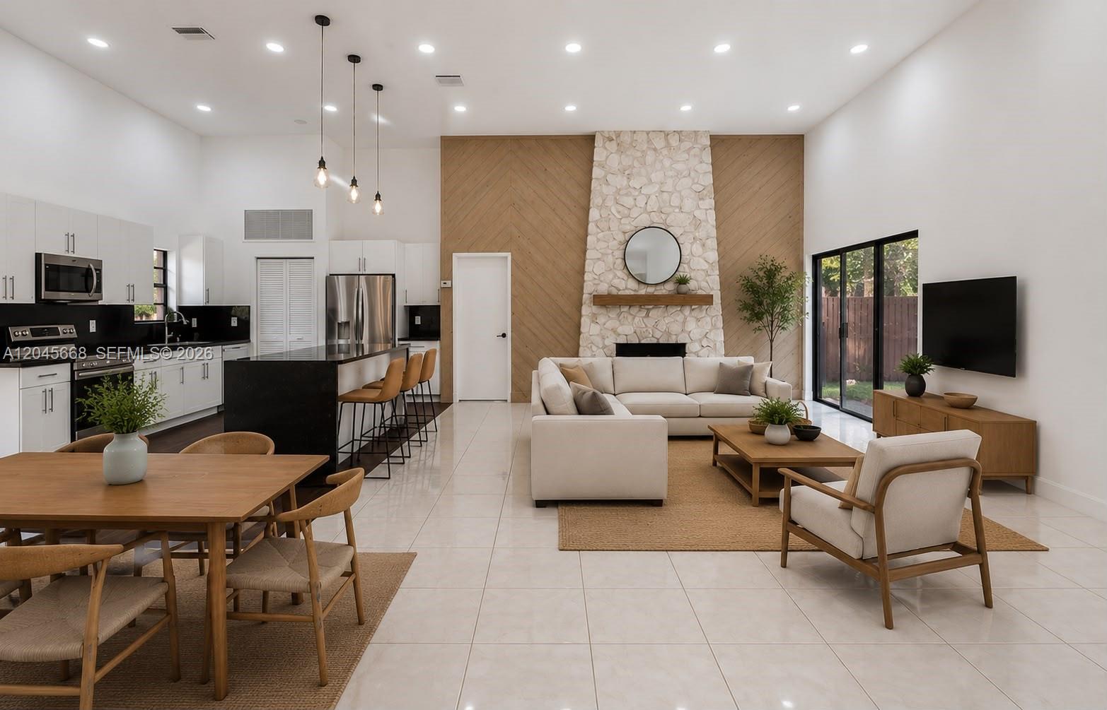 A modern open-concept living area features a stone fireplace, kitchen island, and light wood accents — 601 Leslie Dr, Hallandale Beach FL 33009, HALLANDALE BEACH, FL