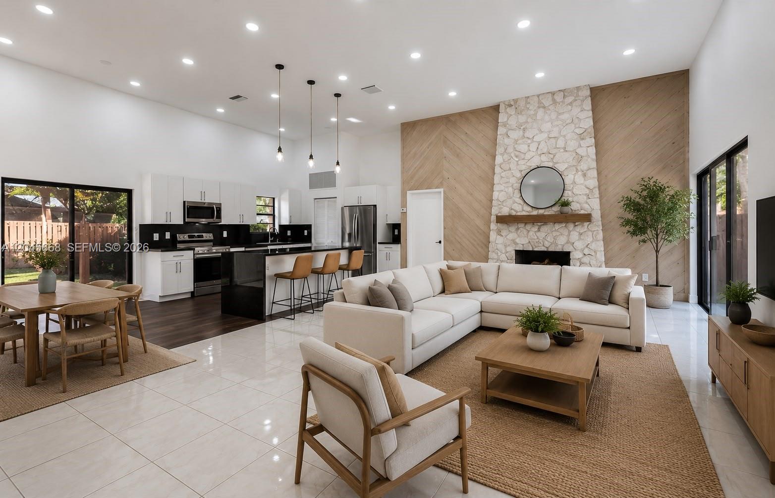 An open-concept living room and kitchen feature a stone fireplace, white cabinetry, and tile flooring — 601 Leslie Dr, Hallandale Beach FL 33009, HALLANDALE BEACH, FL