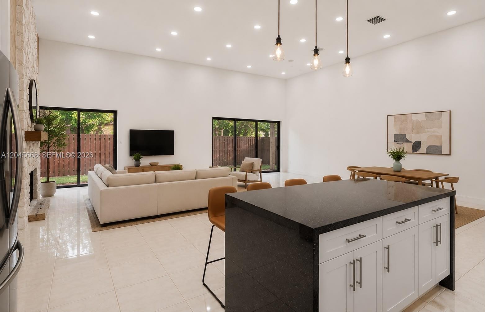 An open-concept living and dining area features a kitchen island, white walls, and sliding doors — 601 Leslie Dr, Hallandale Beach FL 33009, HALLANDALE BEACH, FL
