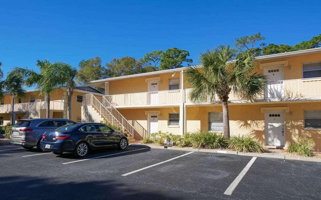 A two-story apartment building with yellow stucco walls, exterior staircases, and a parking lot — 942 LA COSTA CIRCLE UNIT 9, SARASOTA, FL