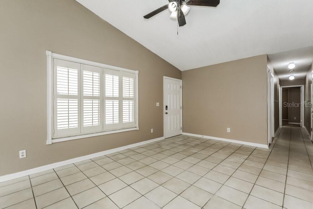 An empty room with beige walls, tile flooring, a window with shutters, and a ceiling fan — 23033 CLEARWATER PLACE, LAND O LAKES, FL