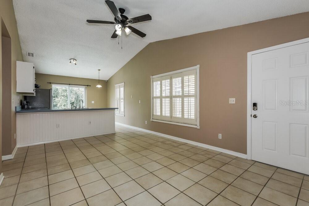 A room with tan walls, tile flooring, a ceiling fan, and a kitchen breakfast bar — 23033 CLEARWATER PLACE, LAND O LAKES, FL