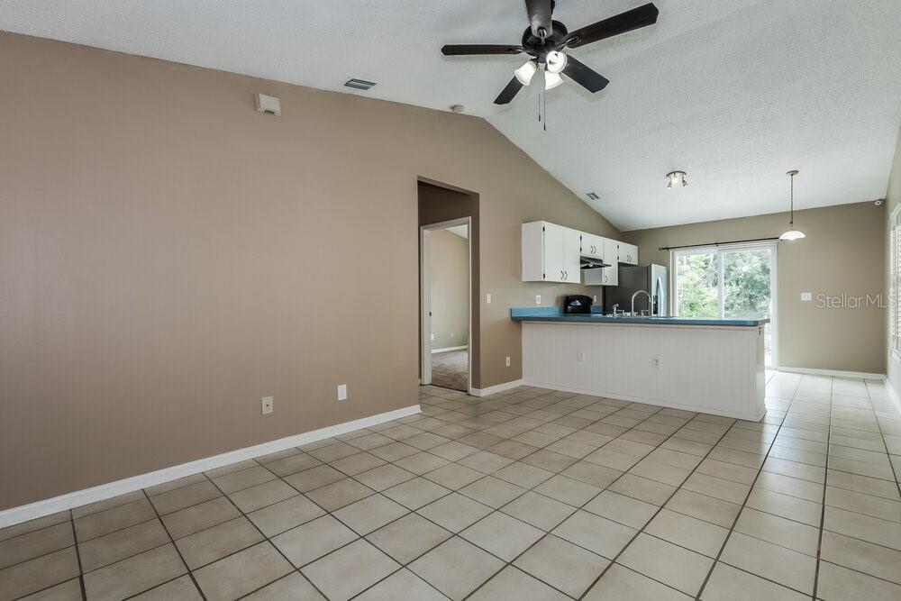 A kitchen with white cabinets and a breakfast bar overlooks an open-concept tiled dining area — 23033 CLEARWATER PLACE, LAND O LAKES, FL