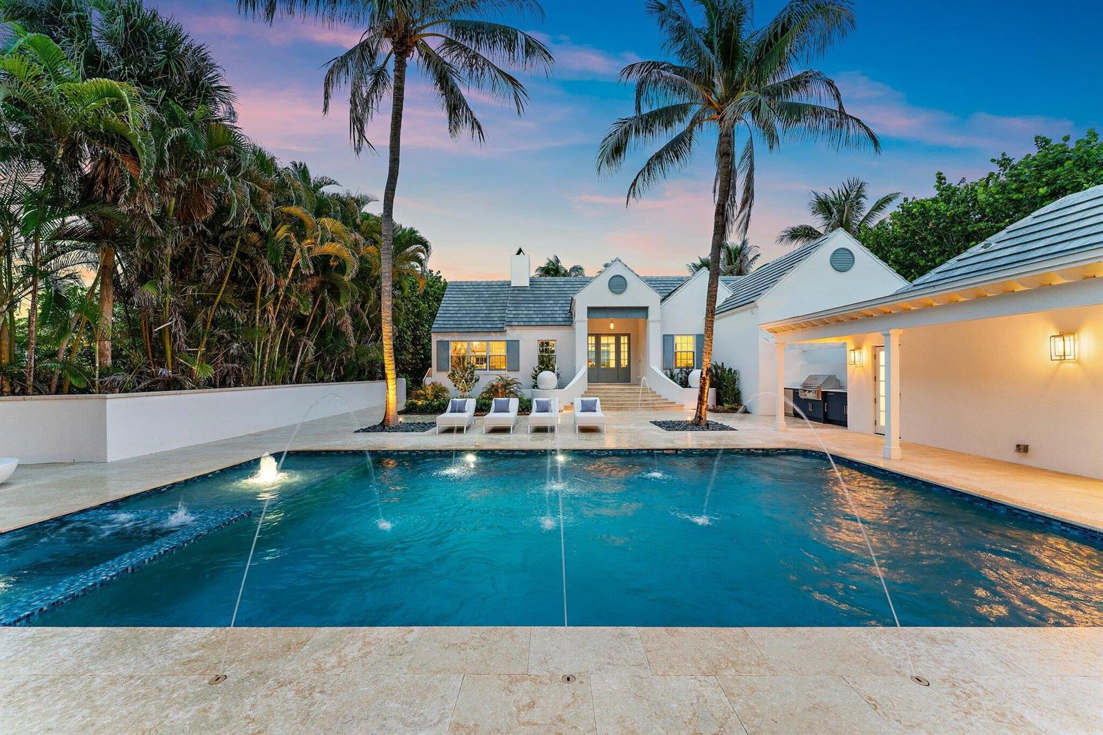 A swimming pool with fountains sits in front of a white house with palm trees — 43 N Beach Road, Hobe Sound FL 33455, HOBE SOUND, FL
