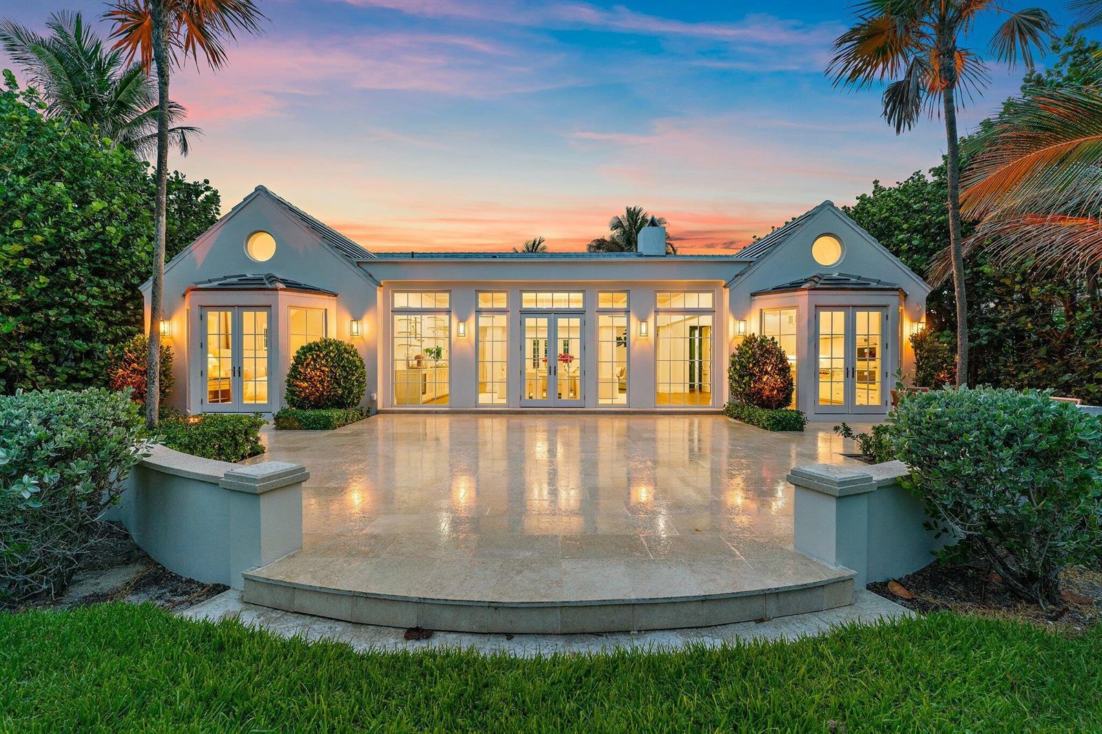 A rear view of a single-story house with a stone patio and large glass doors — 43 N Beach Road, Hobe Sound FL 33455, HOBE SOUND, FL