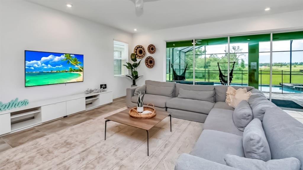 A living room features a grey sectional sofa, a television, and large sliding glass doors — 8962 HILTON RIDGE AVENUE, KISSIMMEE, FL