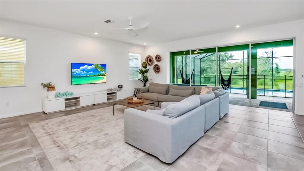 A living room features a large sectional sofa, a wall-mounted television, and sliding glass doors — 8962 HILTON RIDGE AVENUE, KISSIMMEE, FL