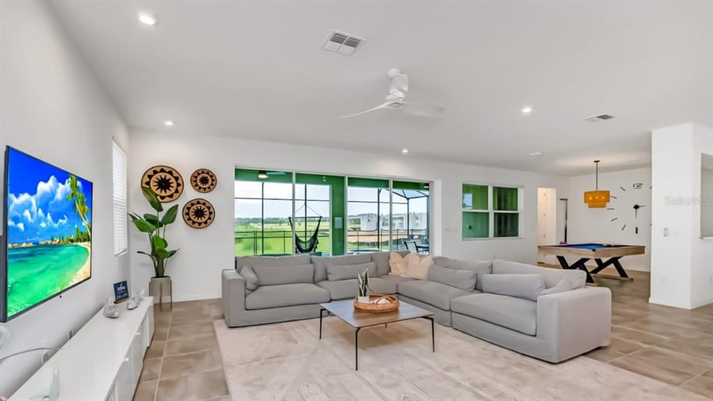 A spacious living room features a large gray sectional, a pool table, and sliding glass doors — 8962 HILTON RIDGE AVENUE, KISSIMMEE, FL