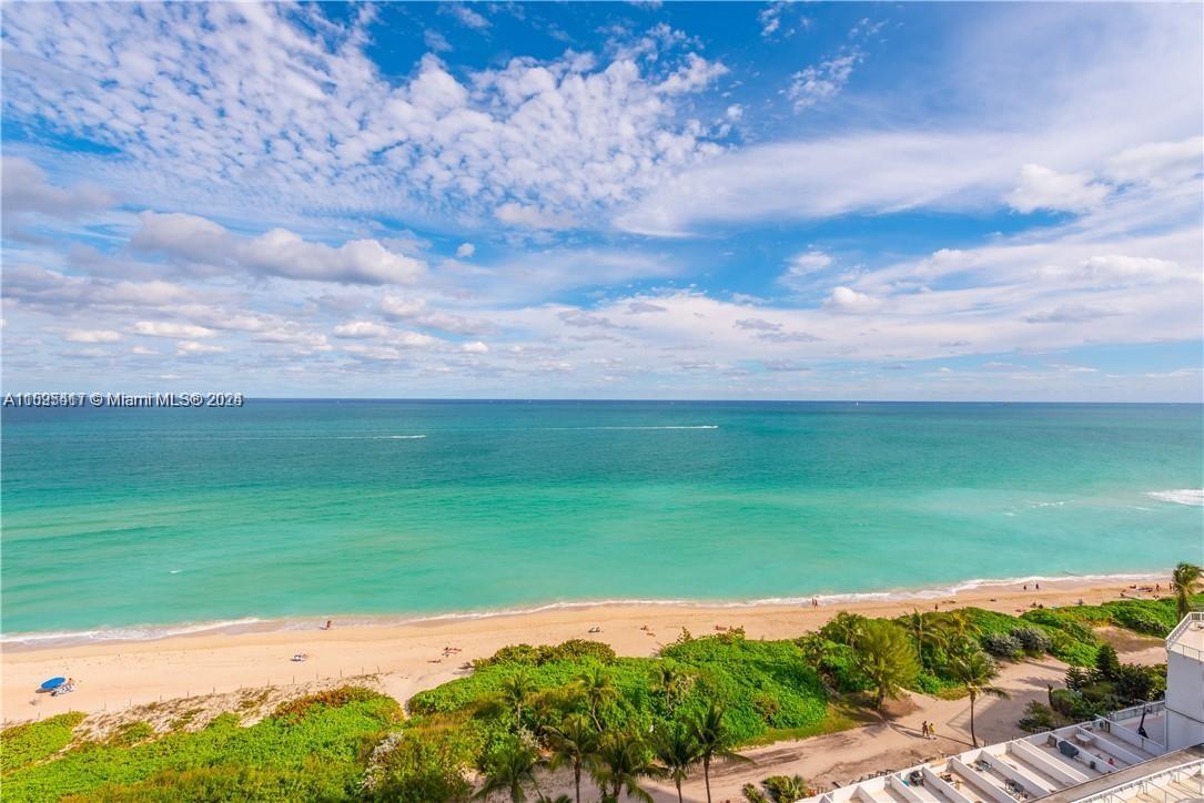 An elevated view of a sandy beach and turquoise ocean under a cloudy blue sky — 5445 Collins Ave # 1135, Miami Beach FL 33140, MIAMI BEACH, FL