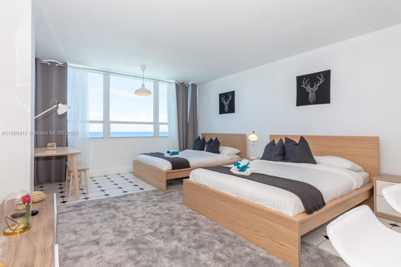 A bedroom with two beds, a gray rug, and a view of the ocean — 5445 Collins Ave # 1135, Miami Beach FL 33140, MIAMI BEACH, FL