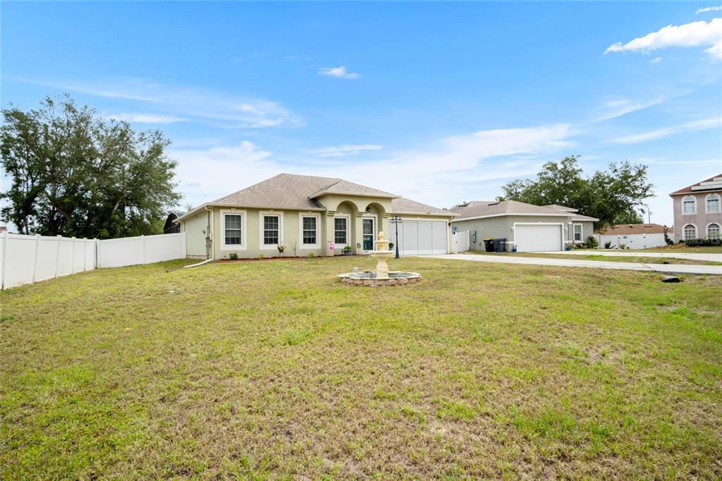 A single-story house with a beige exterior, a front fountain, and a white vinyl fence — 203 FLOUNDER PLACE, POINCIANA, FL