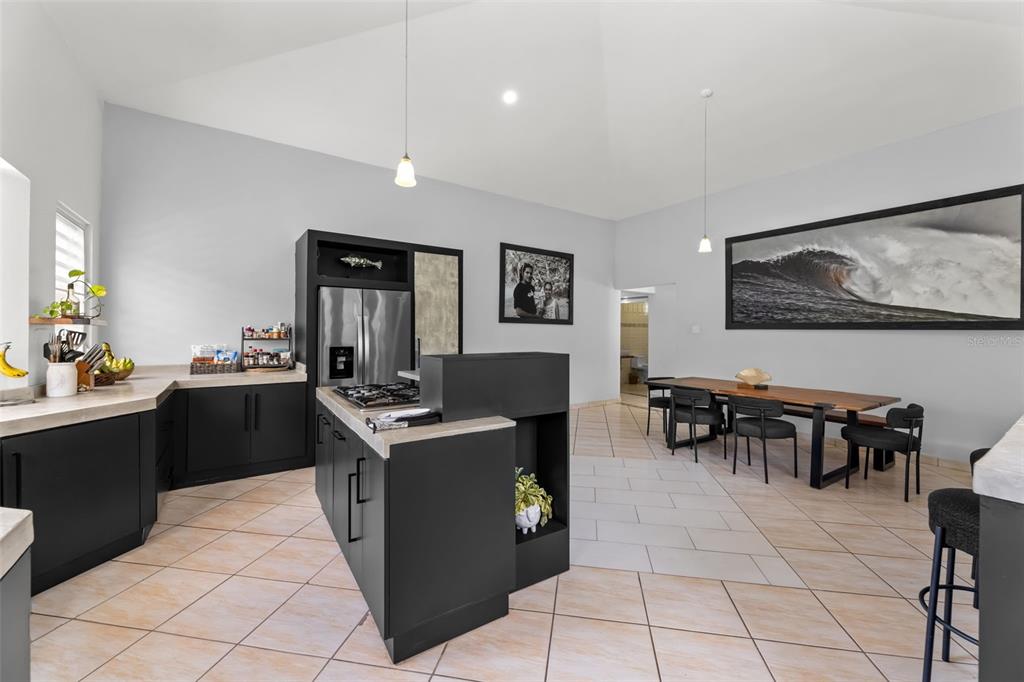 A kitchen with dark cabinetry, a central island, and an adjacent dining area — Lote 30 BARRIO ENSENADA, RINCON, PR