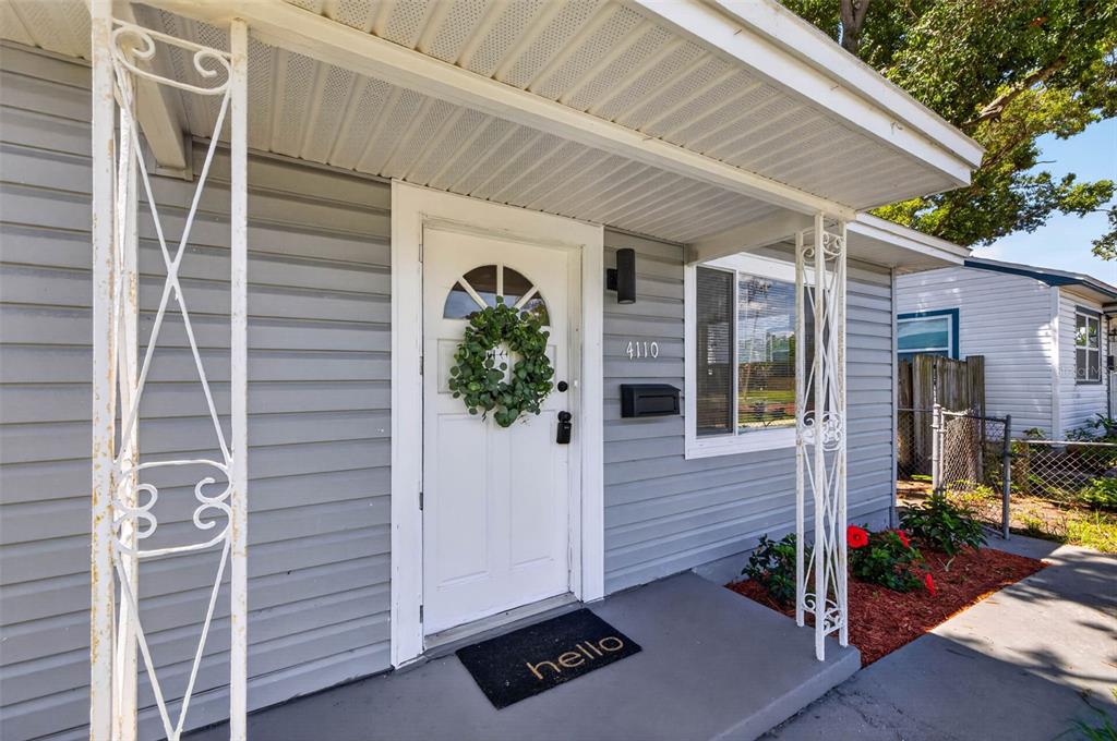 The exterior of a house features gray siding, a white front door, and decorative metal columns — 4110 3RD AVENUE S, ST PETERSBURG, FL