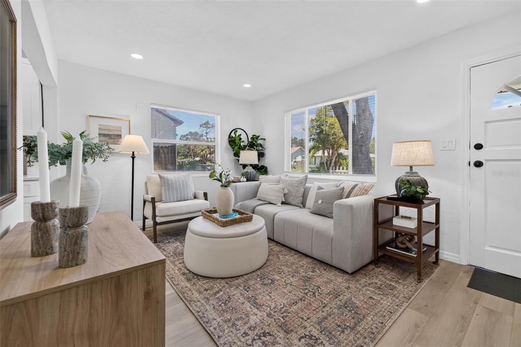 A bright living room features a gray sofa, a round ottoman, and a patterned area rug — 4110 3RD AVENUE S, ST PETERSBURG, FL