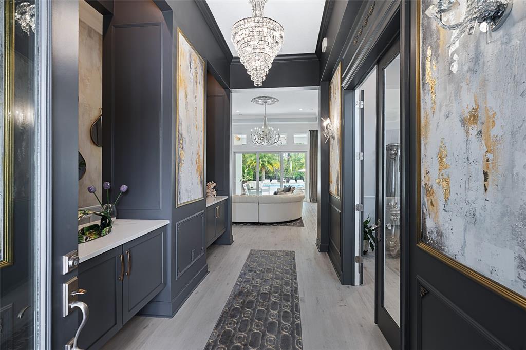 A dark-walled entryway features a crystal chandelier, built-in cabinetry, and a view into the living room — 241 CONSERVATORY DRIVE, PALM COAST, FL