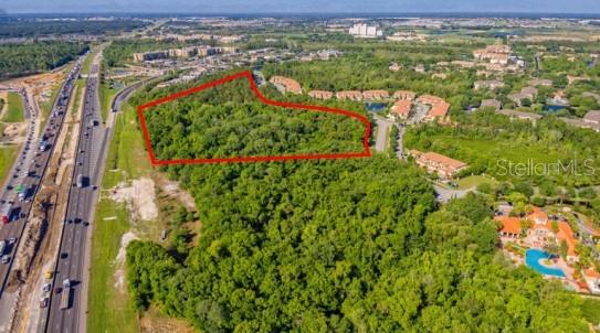 An aerial view shows a wooded lot outlined in red next to a highway — S GOODMAN ROAD, KISSIMMEE, FL