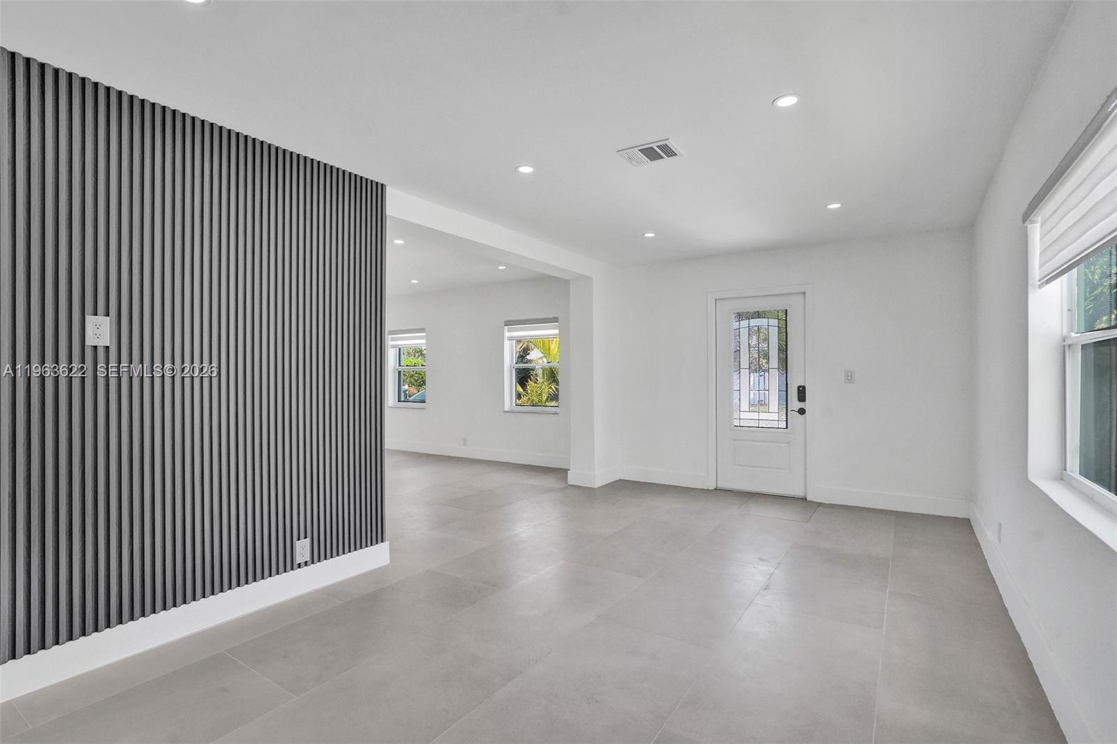 A bright room features light tile floors, white walls, and a grey slatted accent wall — 1010 N 16th Ave, Hollywood FL 33020, HOLLYWOOD, FL