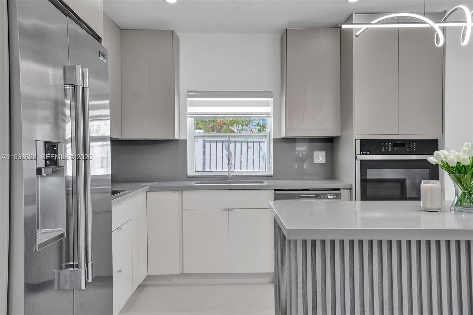 A modern kitchen features gray cabinets, stainless steel appliances, and a gray island with fluted detailing — 1010 N 16th Ave, Hollywood FL 33020, HOLLYWOOD, FL