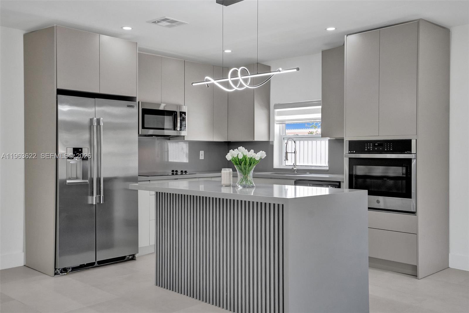 A modern kitchen features gray cabinetry, stainless steel appliances, and a slatted kitchen island — 1010 N 16th Ave, Hollywood FL 33020, HOLLYWOOD, FL