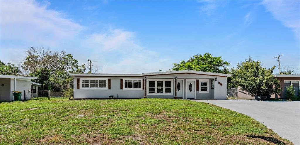 A single-story house with a light gray exterior, white trim, and a large front lawn — 815 W HIGHLAND DRIVE, COCOA, FL