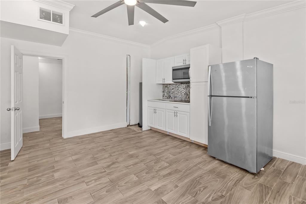A kitchen area features white cabinets, stainless steel appliances, and light wood-look tile flooring — 815 W HIGHLAND DRIVE, COCOA, FL